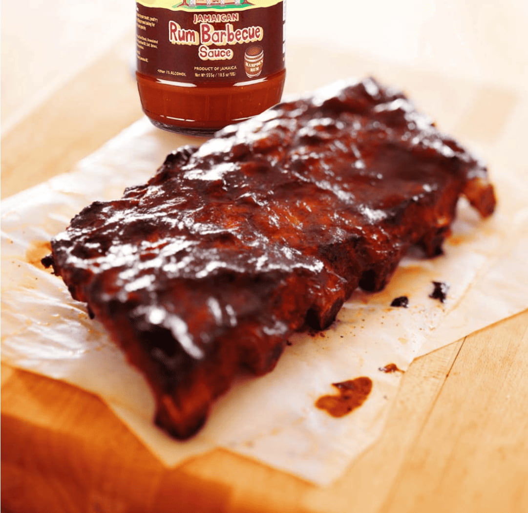 Bbq ribs on a cutting board with a bottle of sauce.
